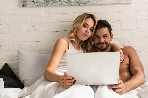 Glückliches Paar am Morgen mit Laptop im Bett — Stockfoto