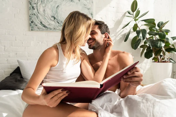 Счастливая пара держит книгу и собирается поцеловаться в постели утром — стоковое фото