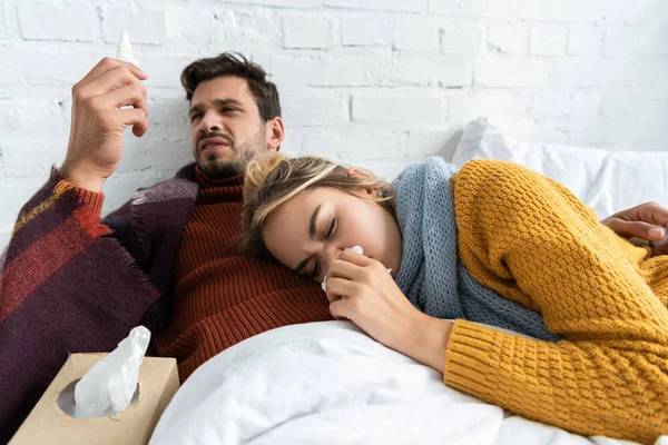 Krankes Paar hält Nasenspray und Servietten im Schlafzimmer — Stockfoto