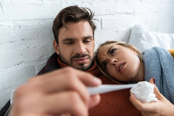 Couple malade avec fièvre tenant thermomètre au lit — Photo de stock