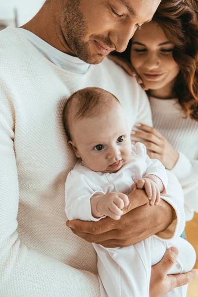 Smiling woman embracing husband holding cute little daughter — Stock Photo