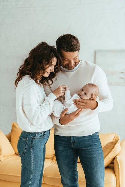 Glückliche Mutter berührt Hand der niedlichen kleinen Tochter, die auf den Händen des Vaters liegt — Stockfoto