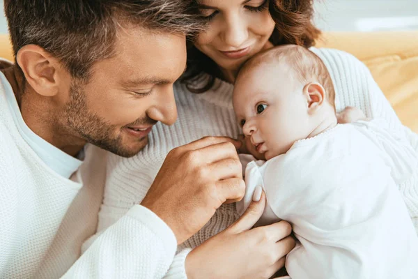 Glücklicher Vater berührt entzückende kleine Tochter, die auf den Händen der Mutter liegt — Stockfoto