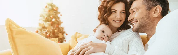 Щасливий чоловік дивиться на усміхнену дружину, що тримає чарівну дитину — стокове фото