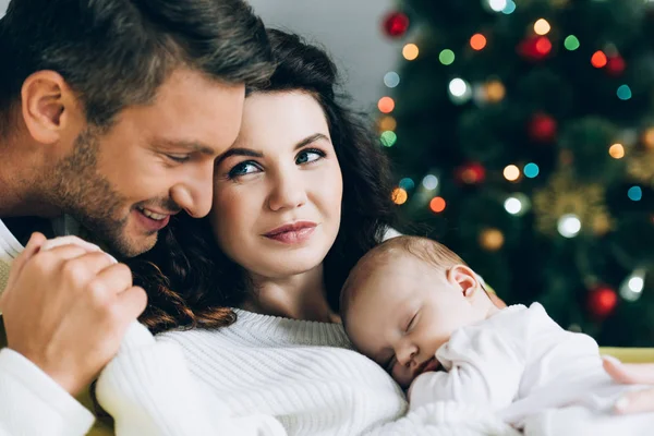 Happy man touching hand of smiling wife holding sleeping baby — Stock Photo