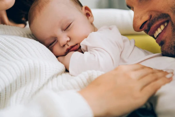 Vista ritagliata del padre sorridente appoggiato sul bambino adorabile sdraiato sulle mani delle madri — Foto stock