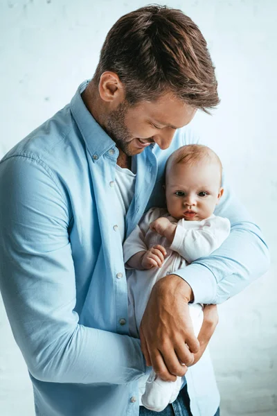 Счастливый отец улыбается, держа в руках милую маленькую дочь — стоковое фото