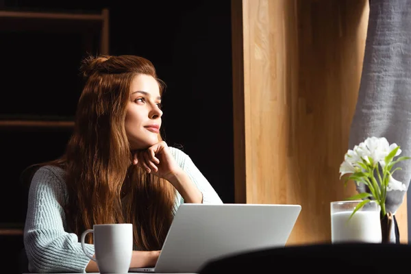Dreamy redhead woman using laptop in cafe with cup of coffee — Stock Photo