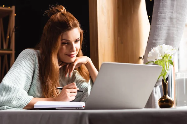 Donna felice che lavora con blocco note e laptop nel caffè — Foto stock
