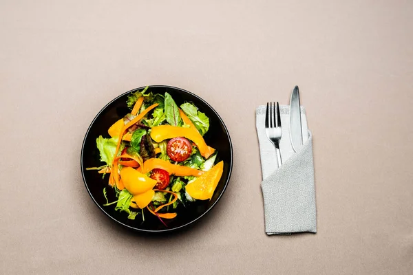 Vue du dessus de la salade dans une assiette avec fourchette et couteau sur la table — Photo de stock