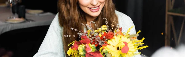 Cropped view of happy woman with bouquet of autumn flowers in cafe — Stock Photo
