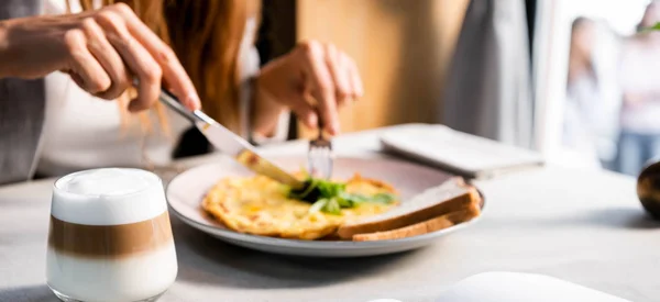 Cropped view of girl with omelet and glass of coffee for breakfast in cafe — Stock Photo