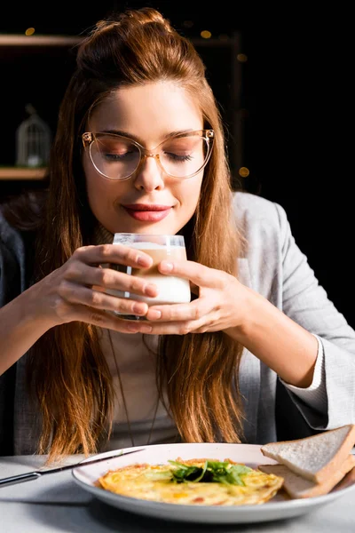 Mulher atraente com olhos fechados segurando vidro de café com café da manhã no café — Fotografia de Stock