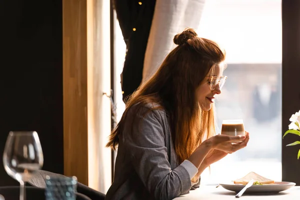 Donna attraente che prende il caffè per la prima colazione nel caffè vicino alla finestra — Foto stock