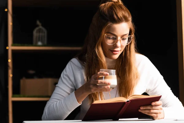 Привлекательная женщина со стаканом книги для чтения кофе в кафе — стоковое фото