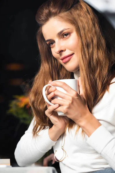 Bela mulher sonhadora segurando xícara de café no café — Fotografia de Stock