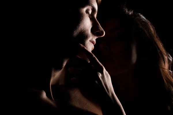 Hermosa pareja sexy abrazos, aislado en negro con luz de fondo - foto de stock