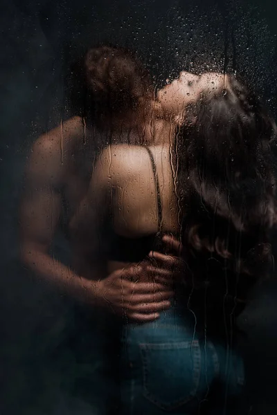 Couple sexy embrasser et embrasser derrière verre mouillé — Photo de stock
