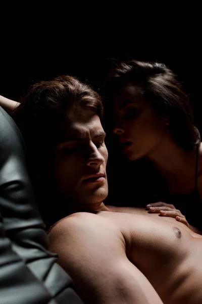 Bella coppia seducente seduta sul divano in camera oscura — Foto stock