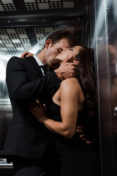 Hombre guapo abrazos y besos hermosa mujer sexy en ascensor - foto de stock