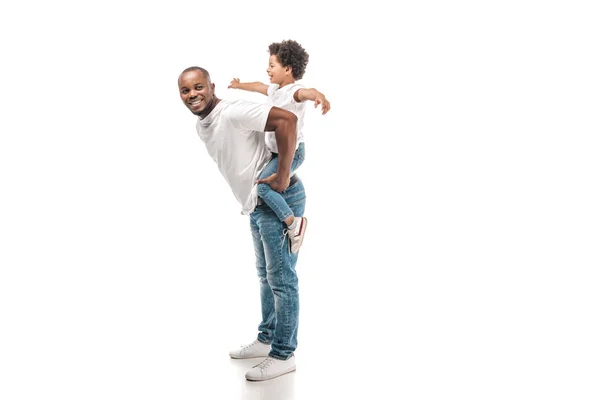 Fröhlich afrikanisch-amerikanischer Mann huckepack entzückenden Sohn und lächelt in die Kamera auf weißem Hintergrund — Stockfoto