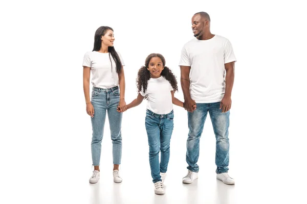 Feliz afroamericano marido y esposa mirando el uno al otro mientras toma de la mano con adorable hija sobre fondo blanco - foto de stock