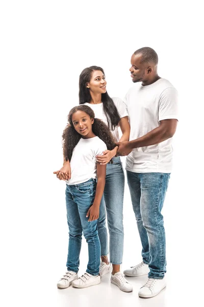 Happy african american husband and wife looking at each other while standing near adorable daughter on white background — Stock Photo