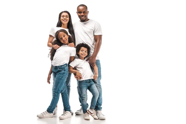 Feliz afroamericano padres con hija e hijo sonriendo a la cámara mientras de pie sobre fondo blanco - foto de stock