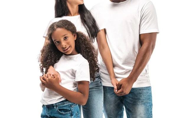 Обрезанный вид африканского американского мужа и жены, держащихся за руки, находясь рядом с очаровательной дочерью, изолированной на белом — стоковое фото