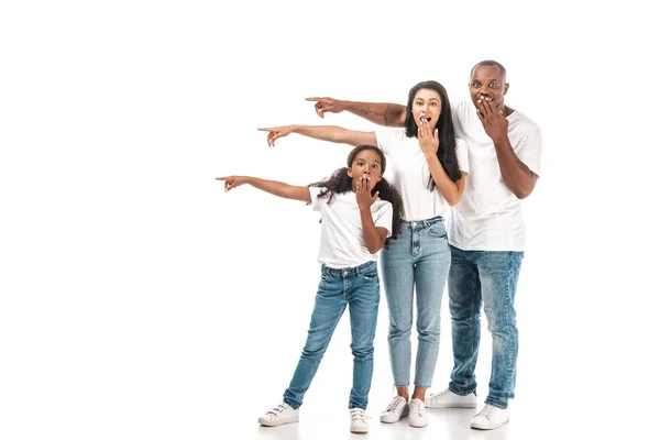 Conmocionados padres afroamericanos señalando con los dedos y cubriendo bocas con las manos sobre fondo blanco - foto de stock