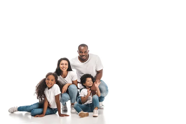 Alegre afroamericano chico saludando mano mientras sentado cerca padres y hermana en blanco fondo - foto de stock