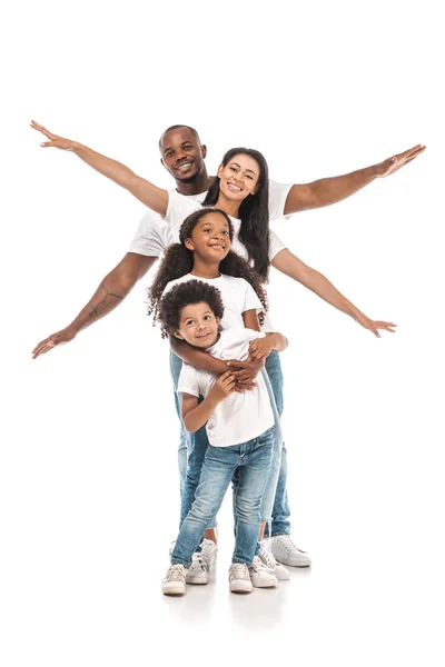 Мила афроамериканська дитина обіймає брата, а веселі батьки імітують політ на білому тлі — стокове фото