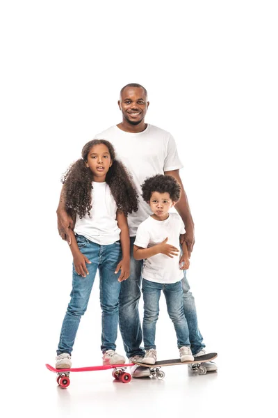 Happy african american man near daughter standing on skateboard, and son on penny board on white background — Stock Photo