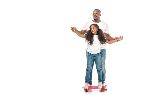 Sorrindo afro-americano pai apoiando adorável filha skate no fundo branco — Fotografia de Stock