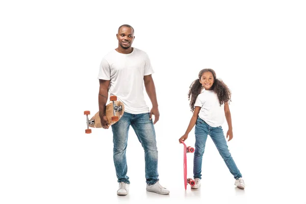 Bel homme afro-américain avec longboard debout près de fille adorable tenant patiner sur fond blanc — Photo de stock