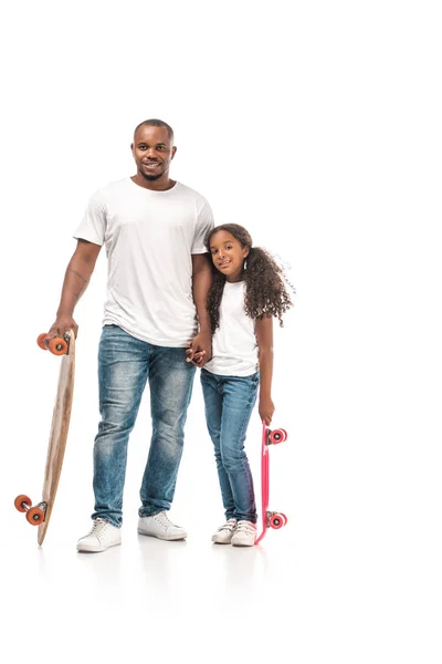 Bonito afro americano homem com longboard perto adorável filha segurando skate no branco fundo — Fotografia de Stock