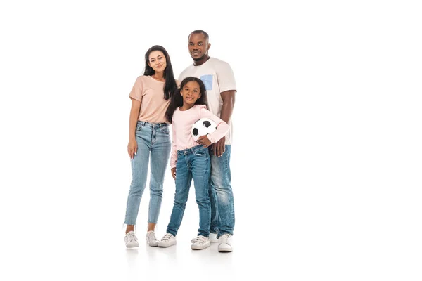 Cute african american kid holding soccer ball while standing near parents on white background — Stock Photo