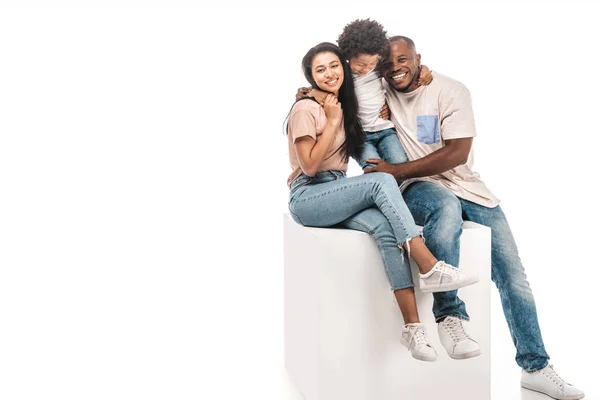 Happy african american family sitting on white cube on white background — Stock Photo