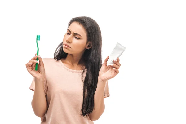 Cético Africano americano mulher segurando escova de dentes e pasta de dentes isolado no branco — Fotografia de Stock