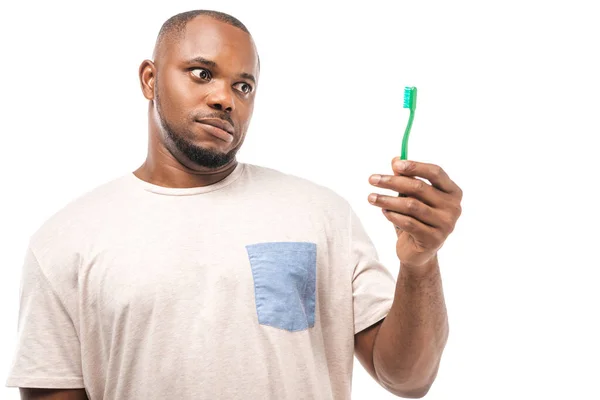 Скептичний афроамериканський чоловік дивиться на зубну щітку ізольовано на білому — стокове фото