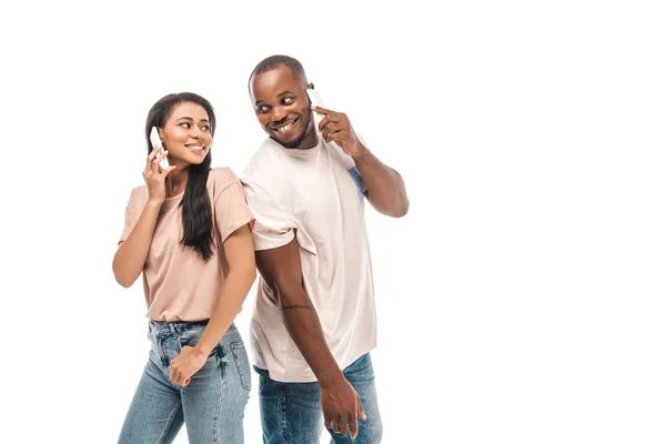 Feliz casal afro-americano olhando um para o outro enquanto fala em smartphones isolados em branco — Fotografia de Stock