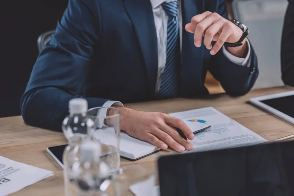 Vista recortada del hombre de negocios en ropa formal sentado en el escritorio en la sala de reuniones — Stock Photo