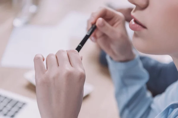 Cropped view of young businesswoman holding pen during business meeting — Stock Photo