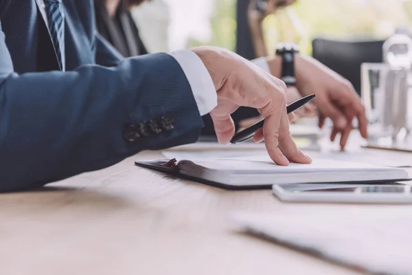 Cropped view of businessman holding pen near notebook at business meeting — Stock Photo