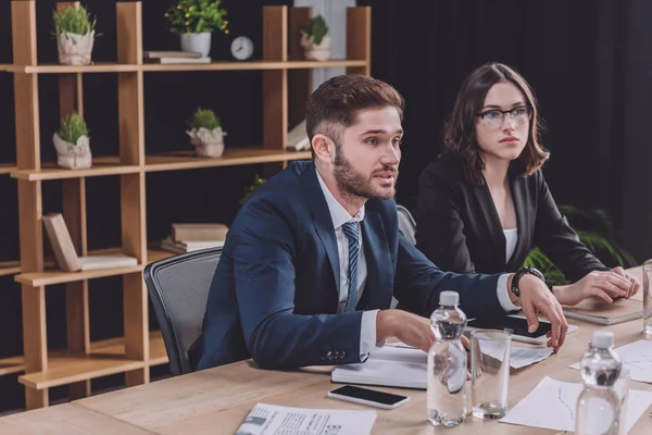 Joven hombre de negocios hablando en reunión de negocios cerca de atractiva mujer de negocios - foto de stock