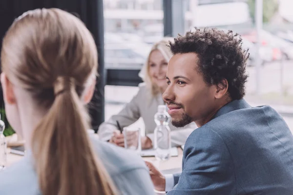 Enfoque selectivo de joven empresario afroamericano mirando a colega durante reunión de negocios - foto de stock
