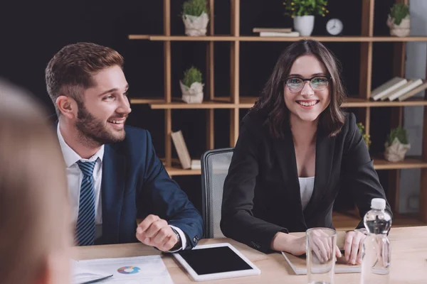 Вибірковий фокус молодого бізнесмена і бізнес-леді, посміхаючись на діловій зустрічі — стокове фото