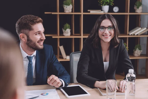 Selective focus of young businessman and businesswoman smiling at business meeting — Stock Photo