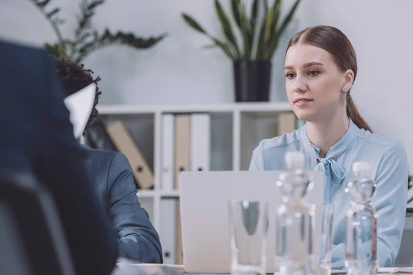 Selective focus of young, pensive businesswoman at business meeting near colleagues — Stock Photo