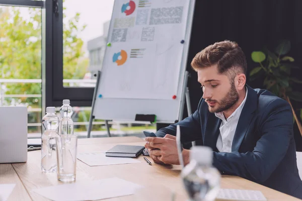 Молодий бізнесмен, використовуючи смартфон, сидячи в кімнаті для переговорів — стокове фото